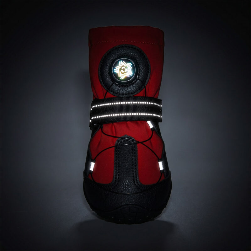 Front close-up of red adjustable secure fit dog shoes highlighting the glowing reflective strap and rotary dial at night.