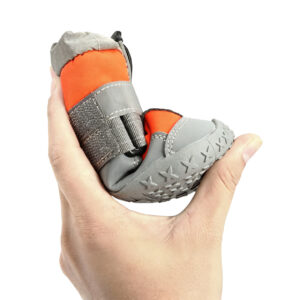 High Elasticity Rubber Sole Flexing Test Hand squeezing an orange canine bootie to demonstrate the lightweight flexible shoes for dogs non-deforming rubber sole.