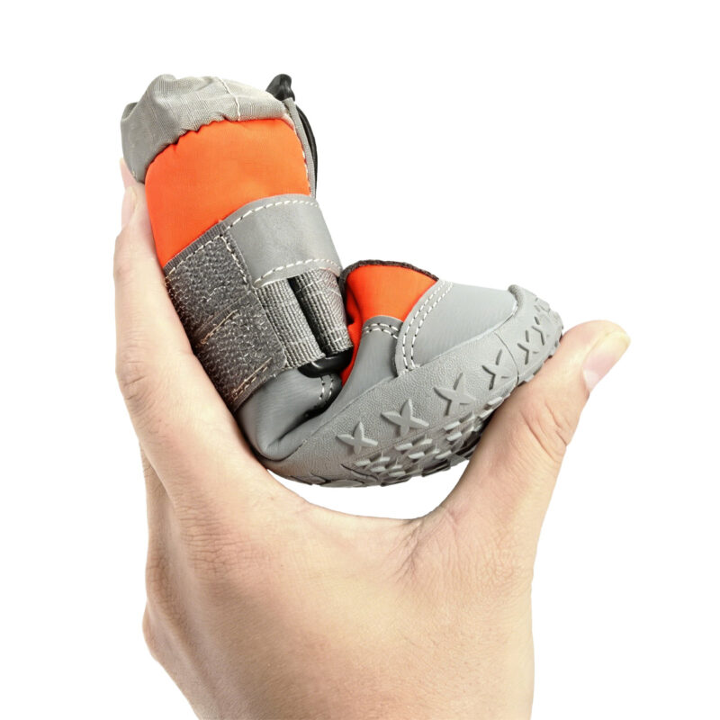 High Elasticity Rubber Sole Flexing Test Hand squeezing an orange canine bootie to demonstrate the lightweight flexible shoes for dogs non-deforming rubber sole.