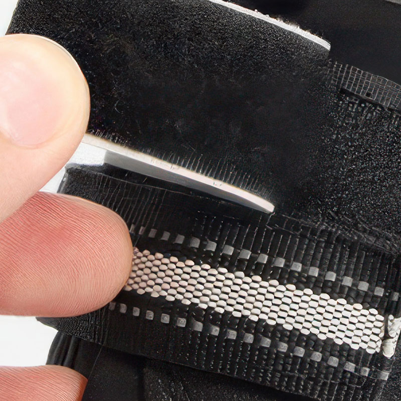 Hand fastening the soft nylon webbing strap and high-brightness reflective safety strips on reflective waterproof pet shoes.