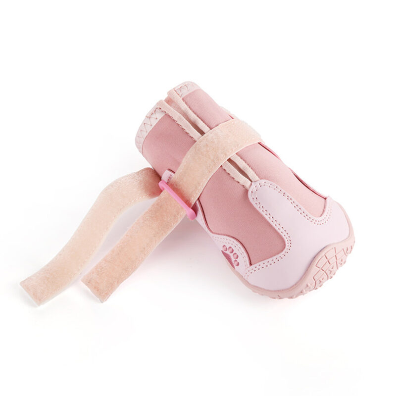 Open Nylon Strap Fastener Detail A single pink snow walking shoe for dogs showing the unfastened adjustable hook and loop reflective ankle strap.