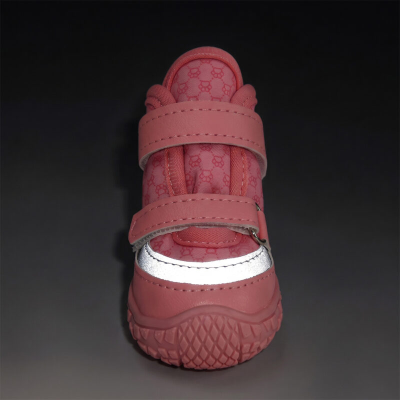 Front angle look at a pink stay-on double velcro dog shoe with its horizontal silver stripe glowing intensely under low light.