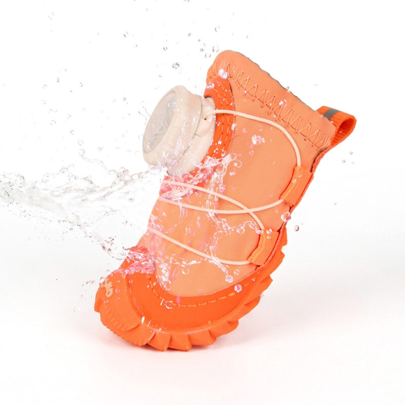 Water splashing over the hydrophobic outer canvas shell of an orange all-weather waterproof dog shoe during a barrier test.