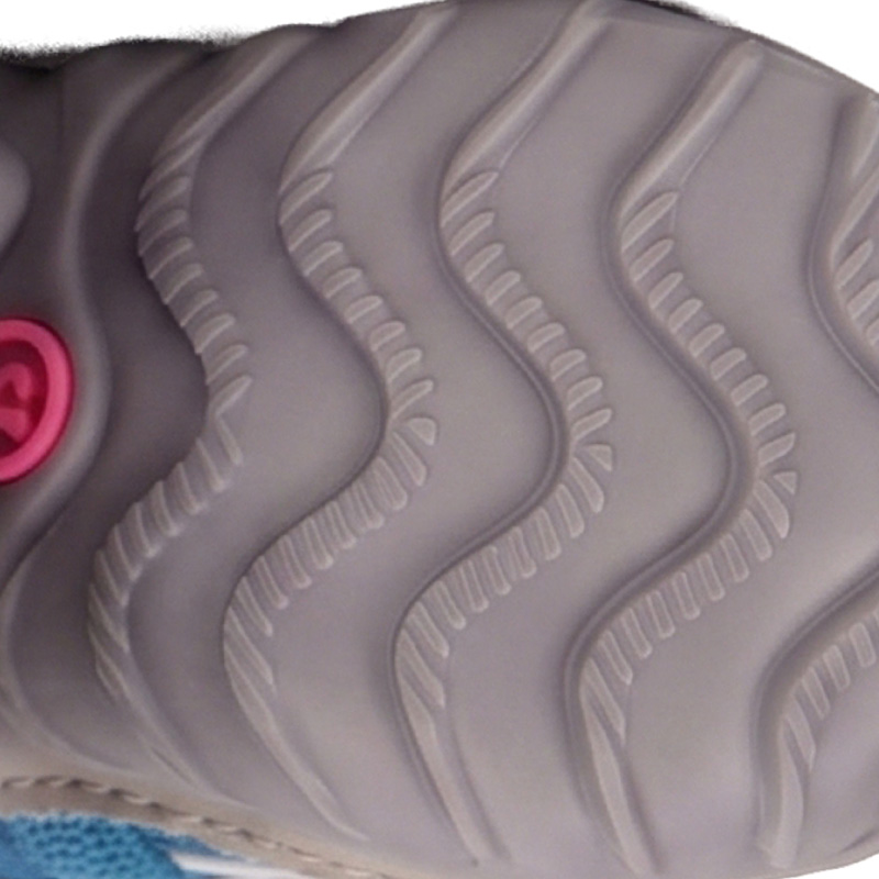 Underneath profile detail of the light gray flexible rubber outsole featuring deep progressive wave tread grooves.