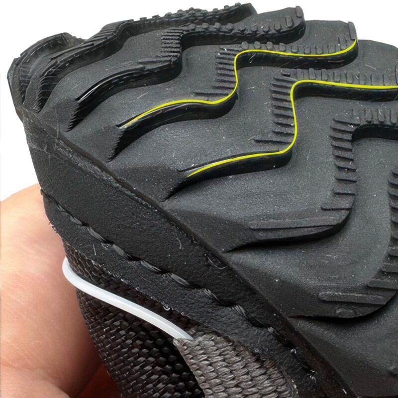 Underneath profile detail of the contoured wave traction tread on a black fleece lined dog shoe outsole.