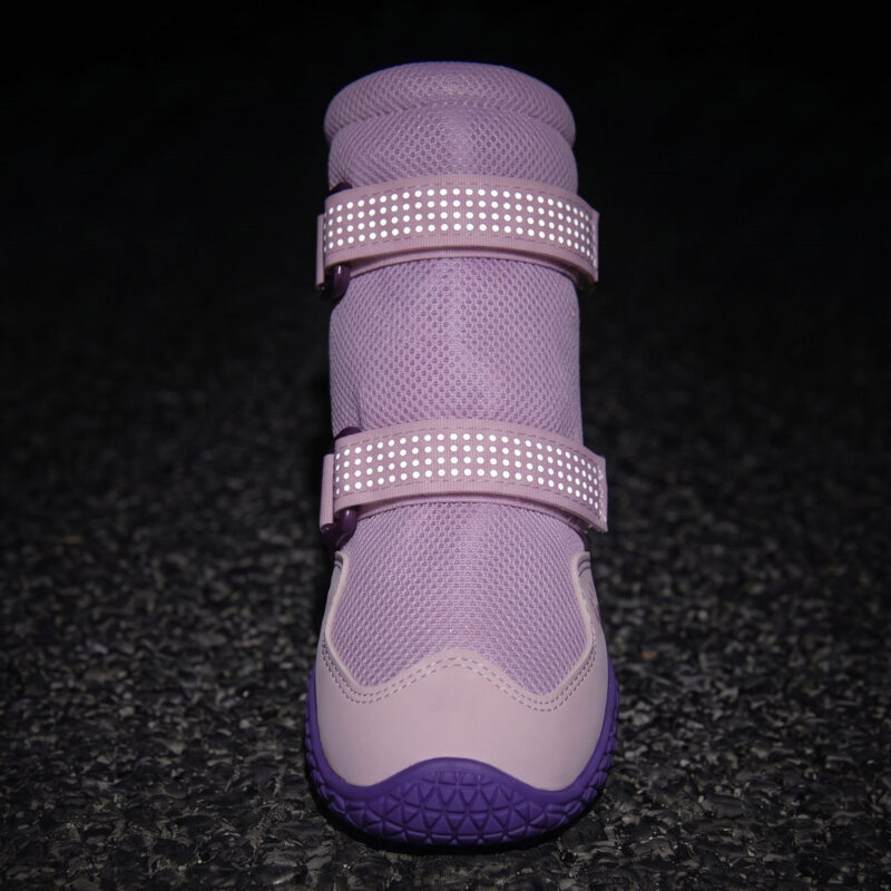 Dual retroreflective straps glowing bright on breathable protective dog boots under dark environment conditions.