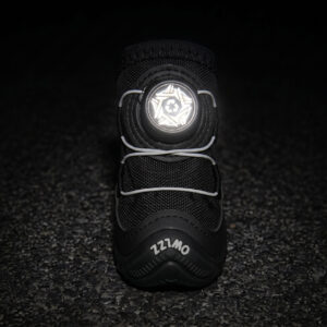 Front view of a black fleece lined dog shoe with its white central wire adjustment dial face glowing under low-light parameters.