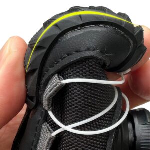 Hand squeezing a black flexible soft-sole winter shoe to demonstrate the high elastic flexion of the rubber base.