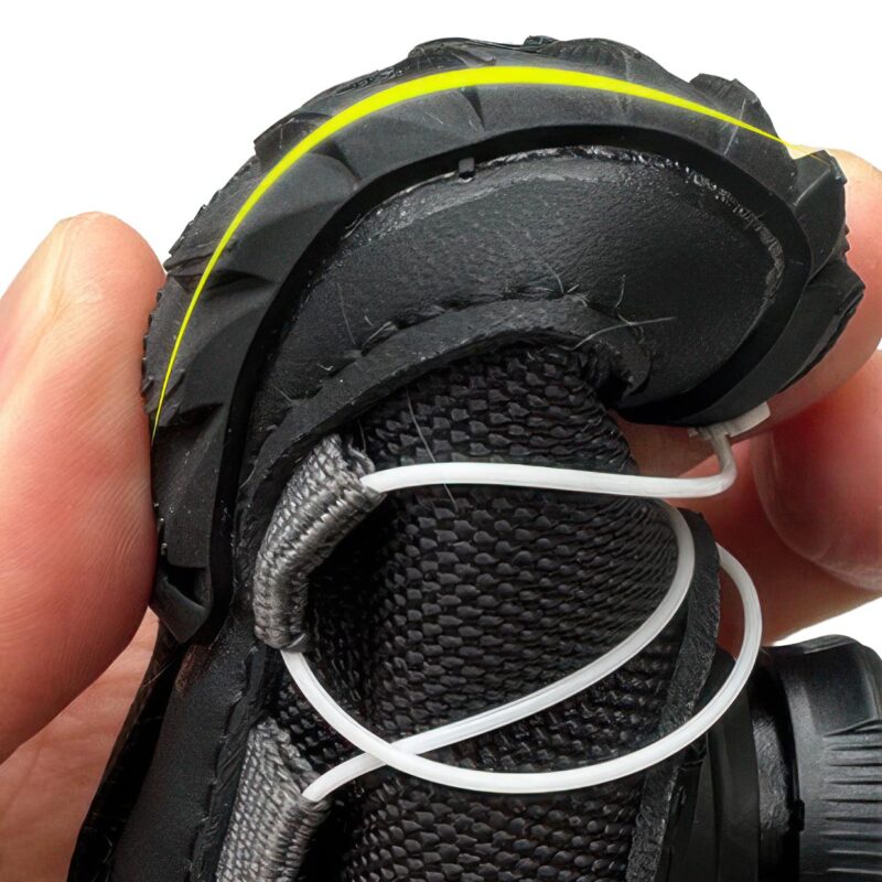 Hand squeezing a black flexible soft-sole winter shoe to demonstrate the high elastic flexion of the rubber base.