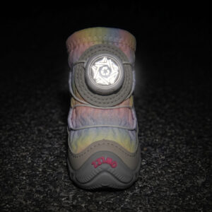 Front view of a unicorn pink dog shoe showing its central circular wire dial glowing brightly under low-light flash conditions.