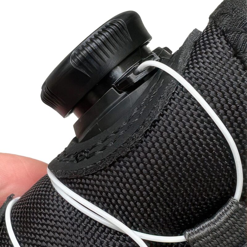 Close up detail of the mechanical dial system pulled outward to release wire lace tension on cold weather shoes.