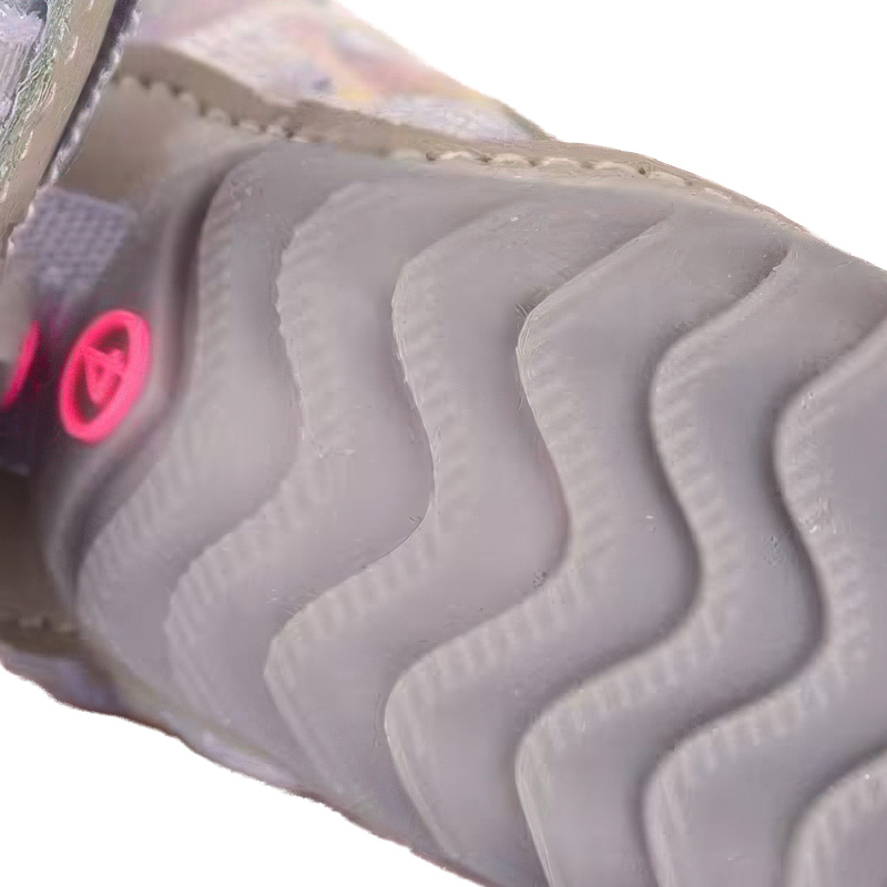 Underneath look at the light gray rubber base layout on luminous weave protective dog shoes showing progressive wave grooves.