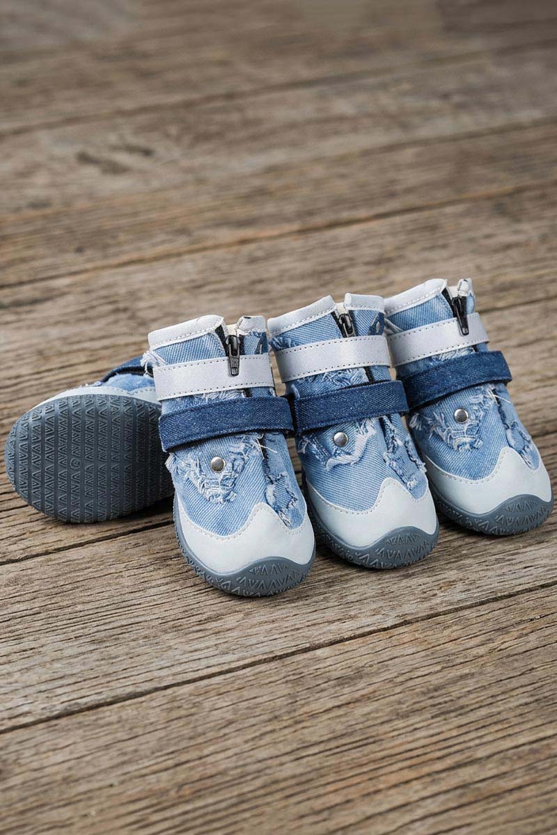Set of four durable denim dog boots with non-slip rubber soles on wooden background.