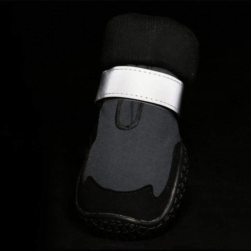 Silver panels glowing bright on reflective protective dog shoes under dark environment conditions for safety.