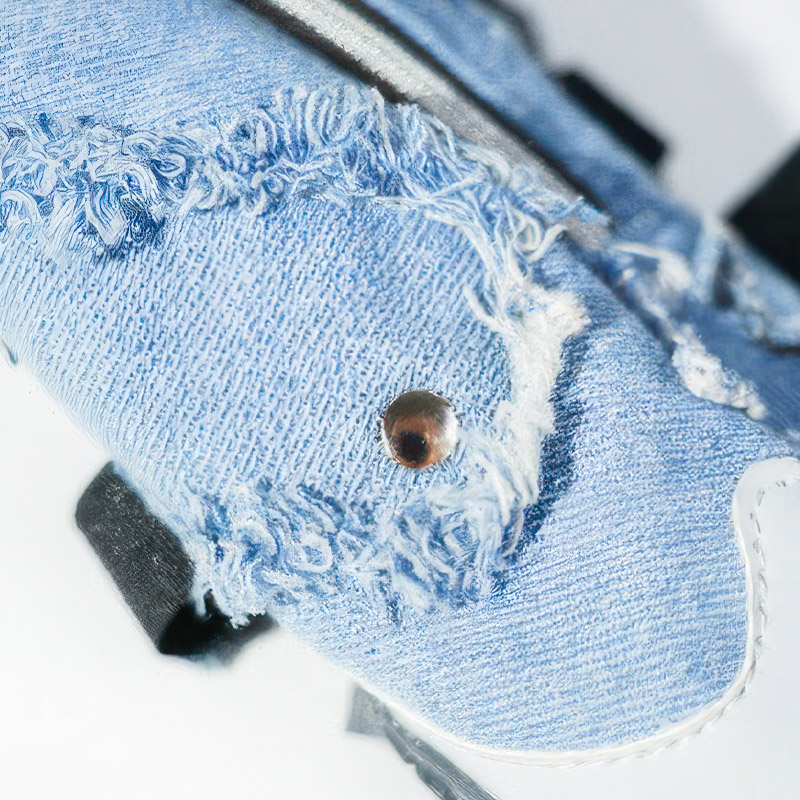 Macro close up of zipper denim dog shoes showcasing the heavy duty distressed canvas and metal rivet accents.